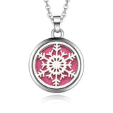 Silver necklace diffuser pendant with white snowflake design on pink background