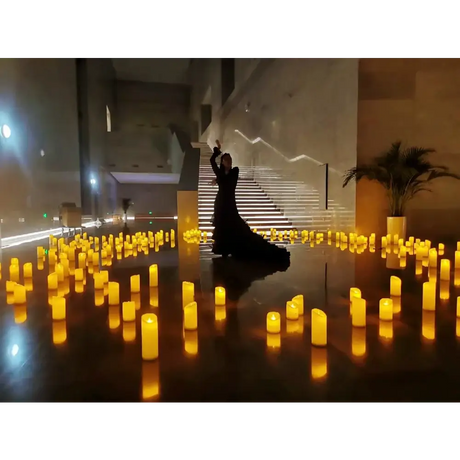 Silhouette in a black gown surrounded by LED flameless candles with real flame effect
