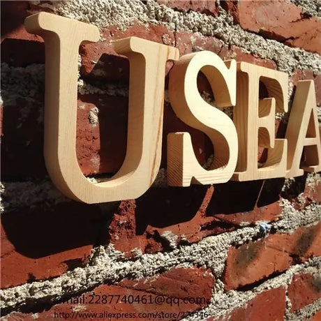 3D unfinished wood letters spelling USEA mounted on a brick wall for home decor
