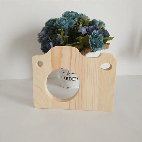 Wooden camera-shaped planter with blue flowers atop unfinished wood letters decoration